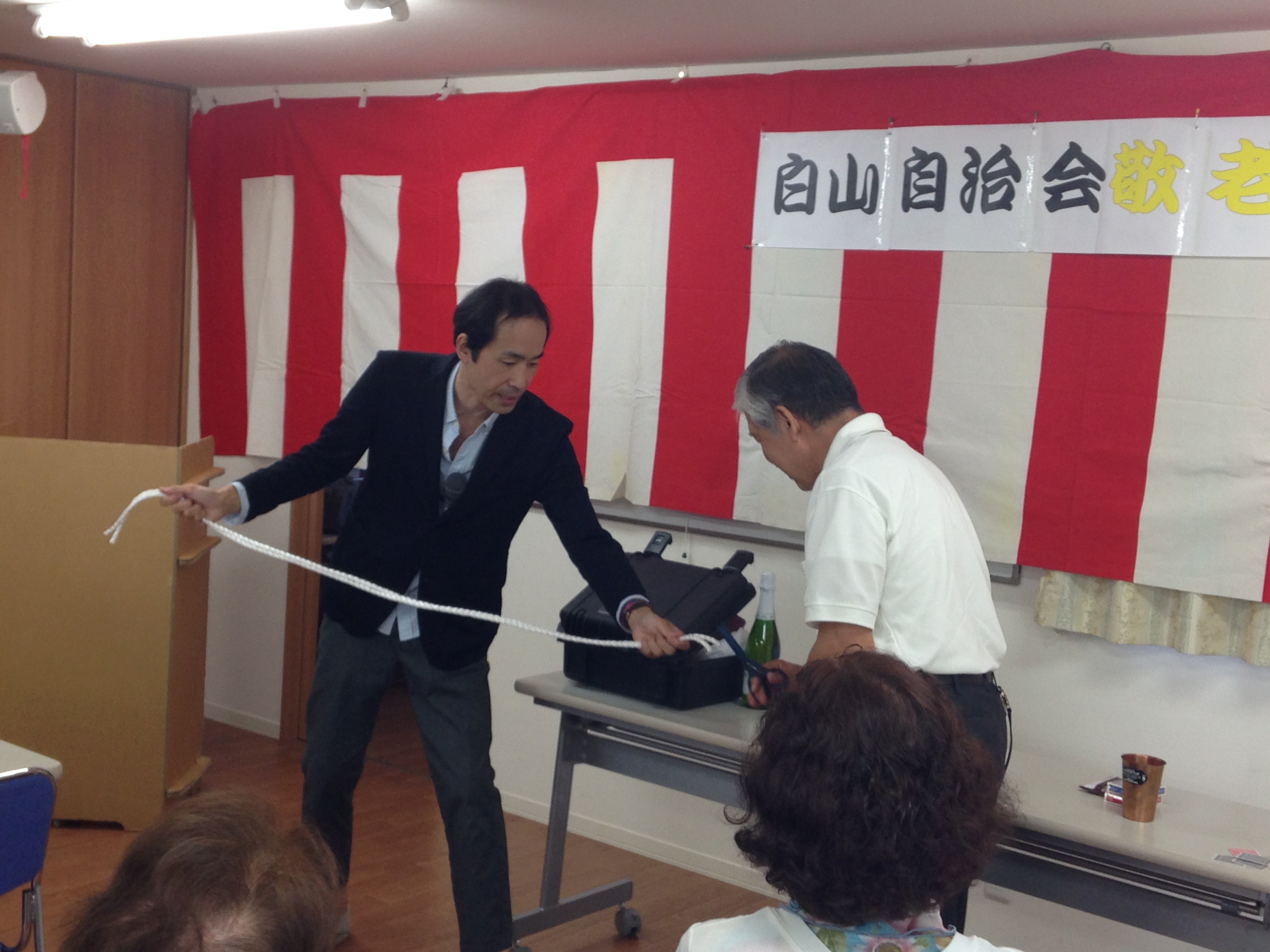 客にロープを真ん中からカットしてもらっている